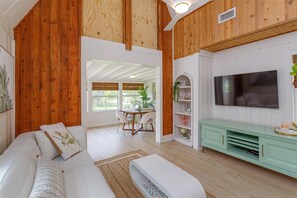 A cozy living room with a wooden ceiling, a white sofa, a dining area with a table and chairs, and a TV mounted on the wall. - Hope House- Vacation Village 1 Bedroom with Loft 2 Home (Clermont)