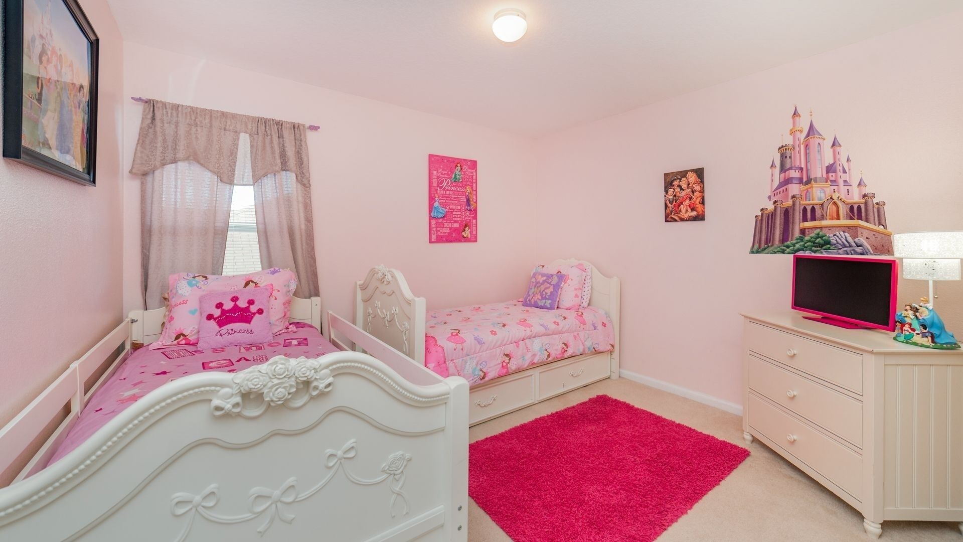 A pink-themed bedroom with two beds, a dresser, and a castle decoration.