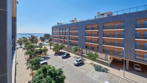 Un hotel de varios pisos con balcones, un estacionamiento y vista al mar.