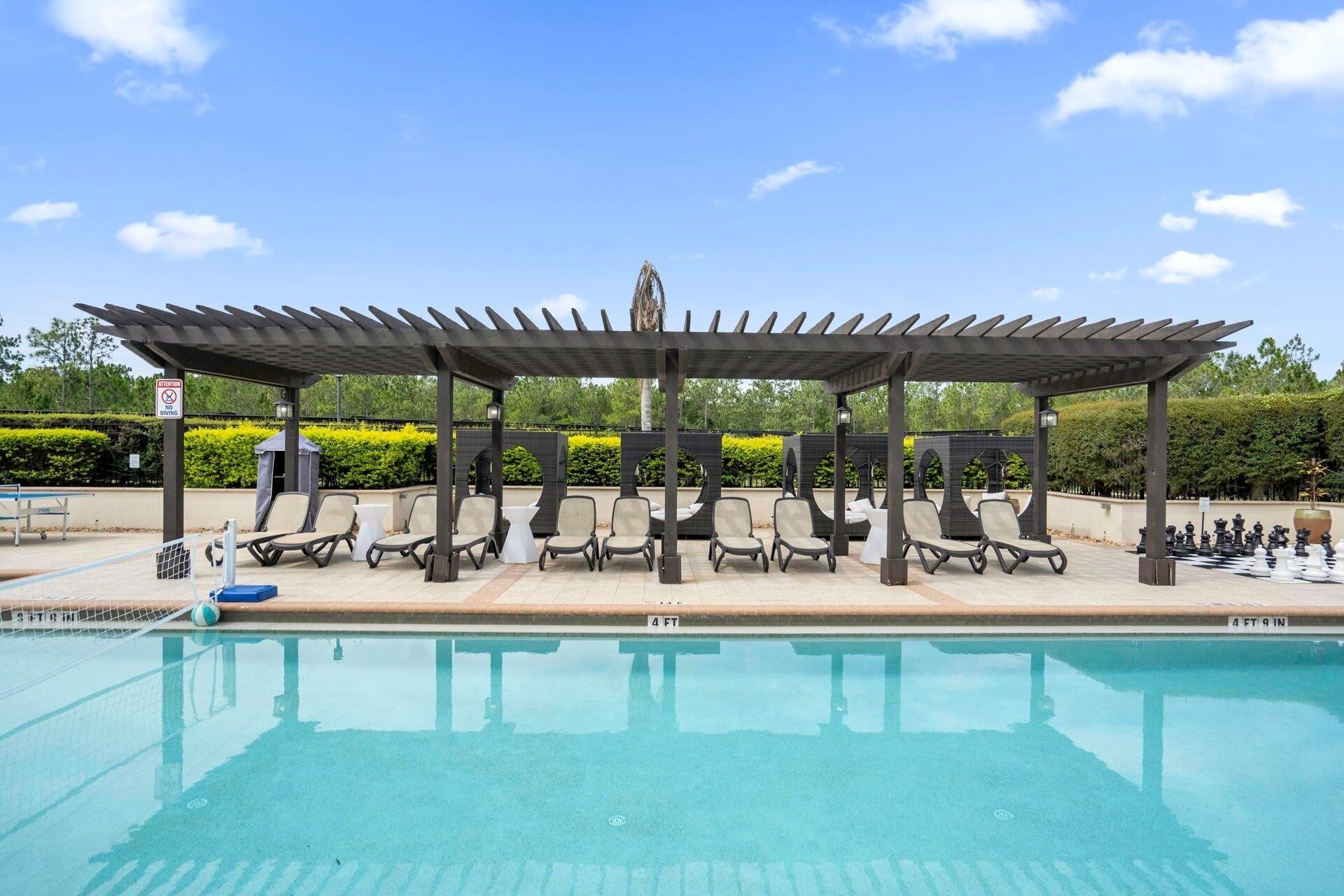 A poolside area with a covered seating area and lounge chairs.