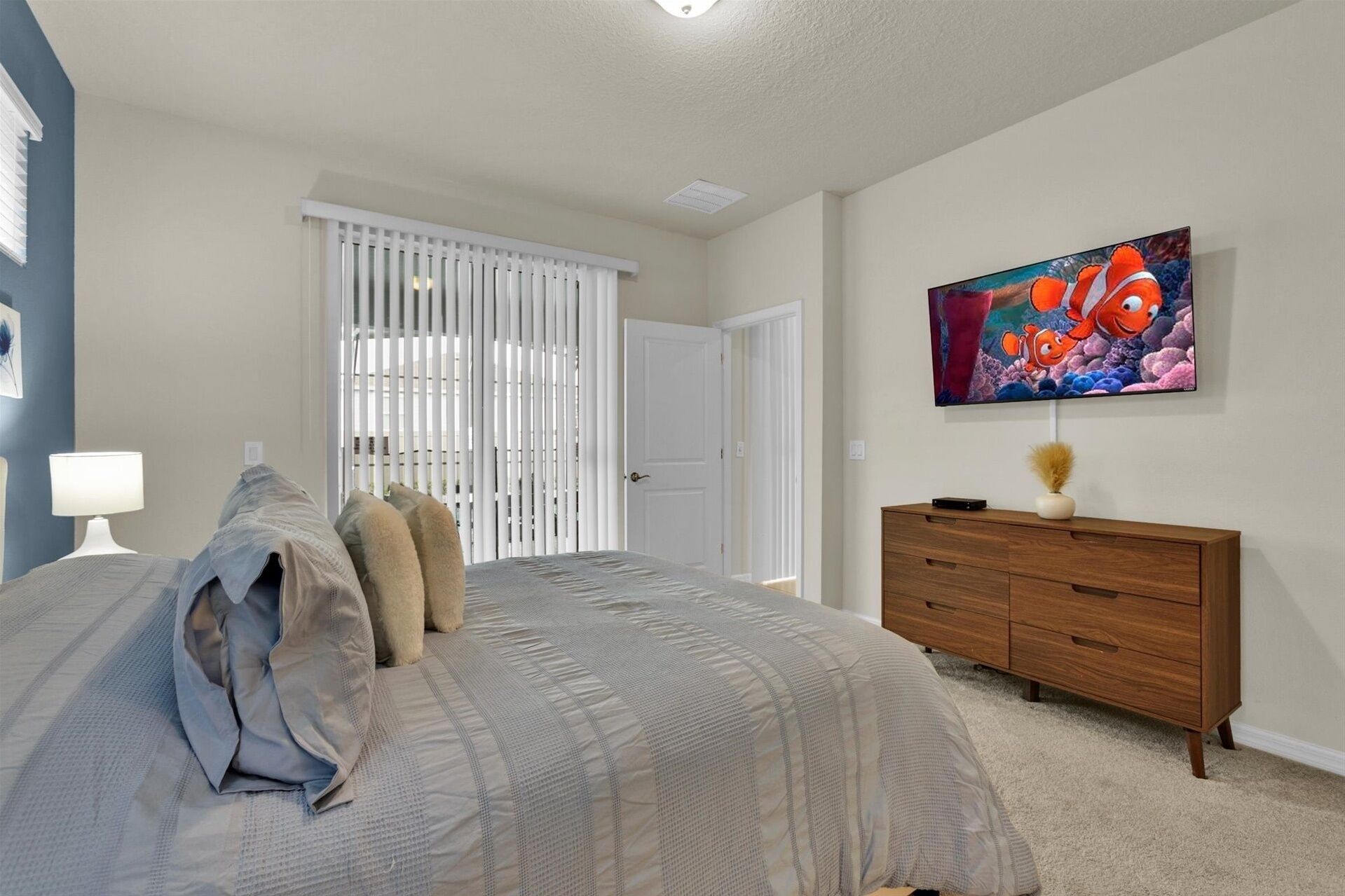 A bedroom with a bed, a dresser, a painting, and a window with blinds.