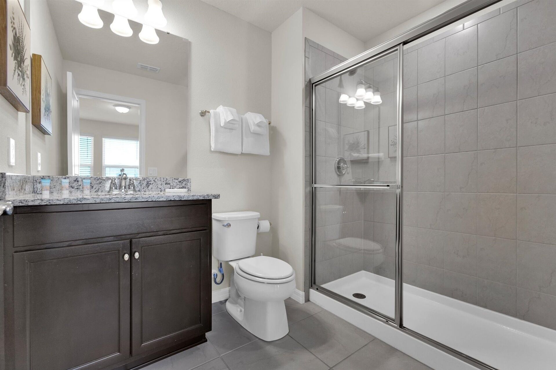 A modern bathroom with a glass-enclosed shower, a marble sink, and a toilet.