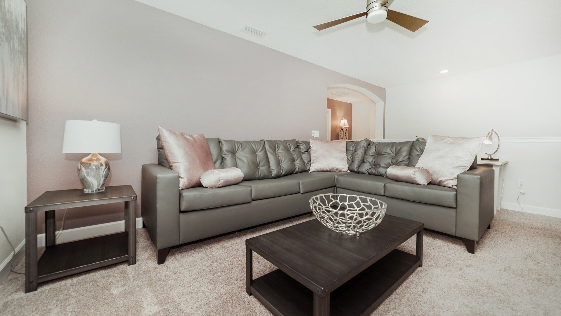 A modern living room with a sectional sofa, a coffee table, and a side table with a lamp.