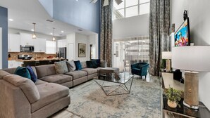A spacious living area with a sectional sofa, a glass coffee table, and a modern ceiling fan. - Storey Lake Resort 5 Bedroom Pool Home with Themed Rooms 5 Home (Kissimmee)