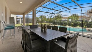 A covered patio with a pool, outdoor seating, and a view of the surrounding area. - Solterra Resort 9 Bedroom Private Pool Home Sleeps 24 9 Home (Davenport)