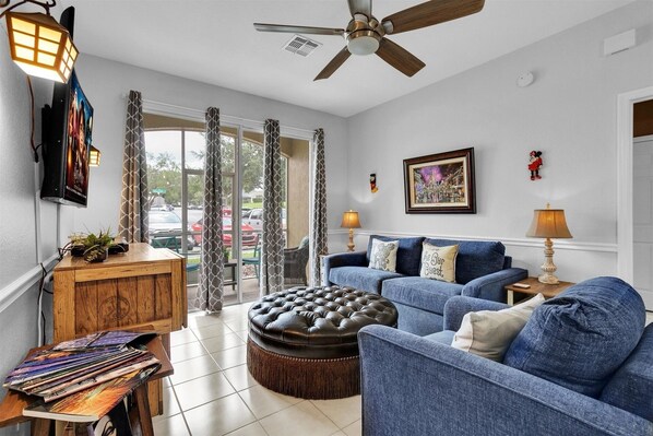 A living room with a blue sofa, a wooden coffee table, and a ceiling fan. - Windsor Palms Resort 1st Flr 3-bdrm Condo Pirate Themed Bedroom 3 Condo (Kissimmee)