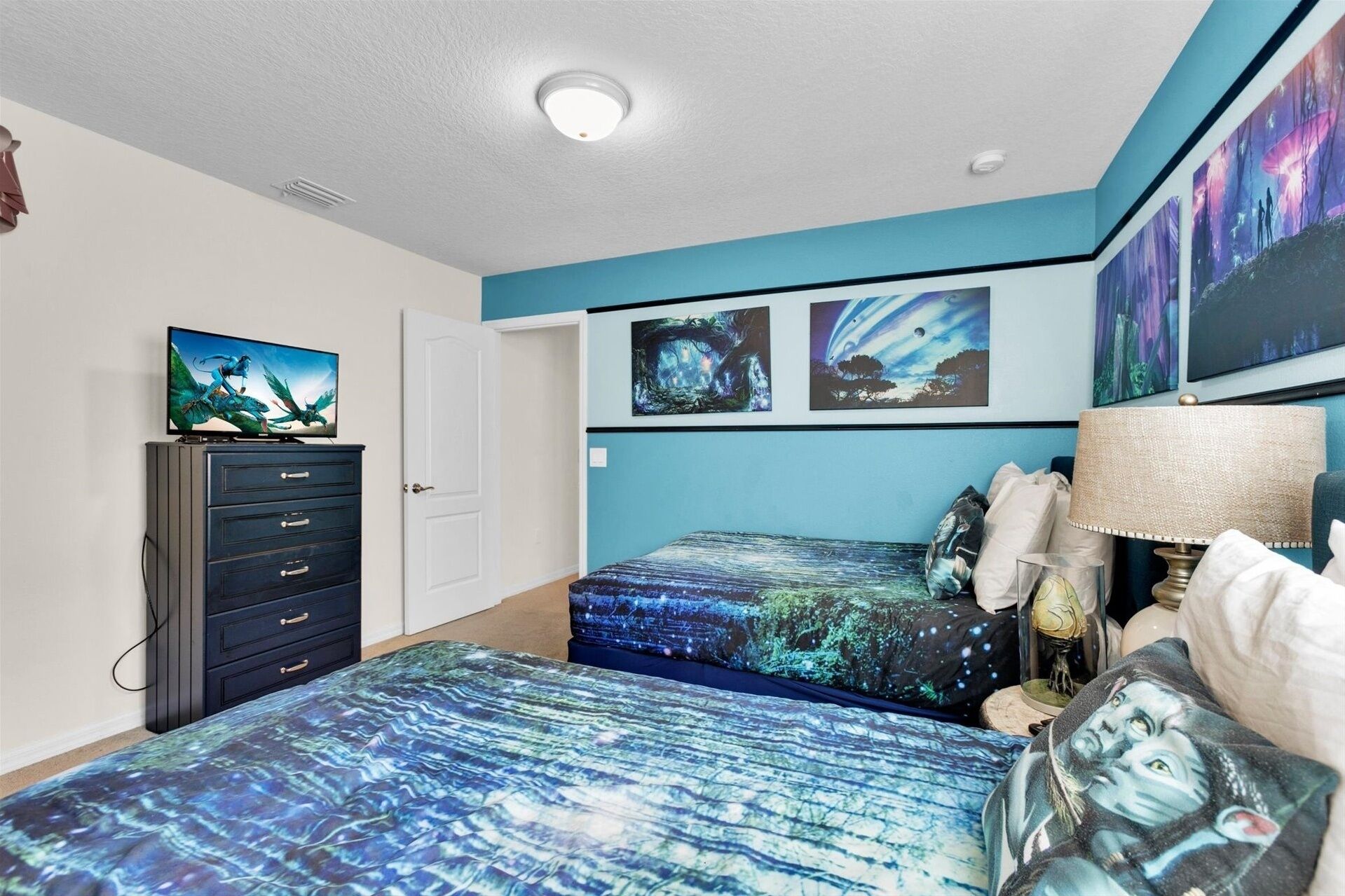 Quarto com duas camas, cômoda e quadros nas paredes.