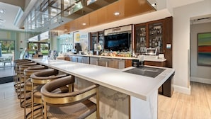 Eine moderne Bar mit einer langen Theke, Barhocker und einem Fernsehbildschirm.
