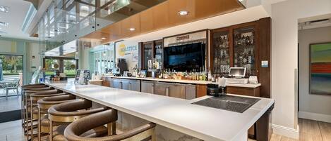 A modern bar area with a long counter, bar stools, and a television screen.