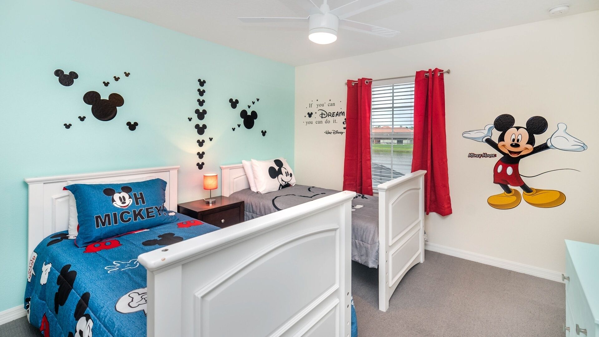A child's bedroom with Mickey Mouse-themed decorations, including wall decals and bedding.