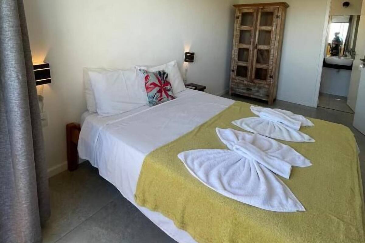 Una habitación de hotel con una cama, un edredón amarillo y toallas dispuestas sobre la cama.