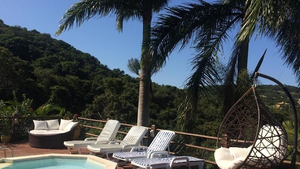 Zona junto a la piscina con hidromasaje, sillas de descanso y una silla colgante.
