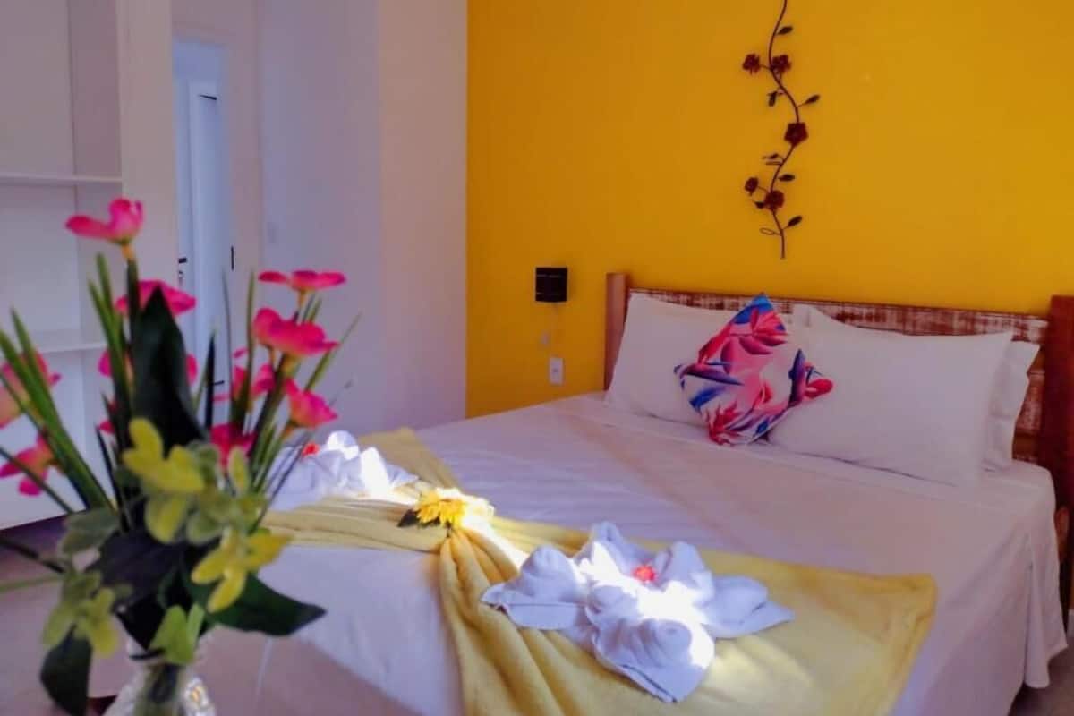 Una habitación de hotel con cama, pared amarilla y un adorno de pared.