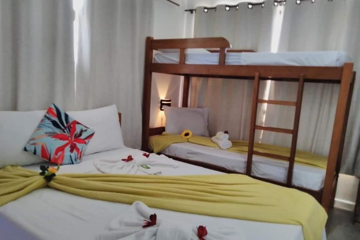 Una habitación de hotel con dos literas, un cojín con estampado floral, toallas y un adorno con forma de sol.