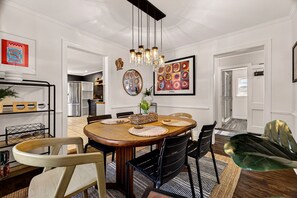 A dining area with a wooden table, black chairs, and a hanging light fixture. - Stylish Ardsley Park Bungalow in Prime Location by Lucky Savannah (Savannah)