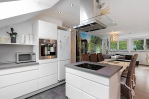Eine moderne Küche mit Backofen, Mikrowelle und Kochinsel mit Induktionskochfeld.