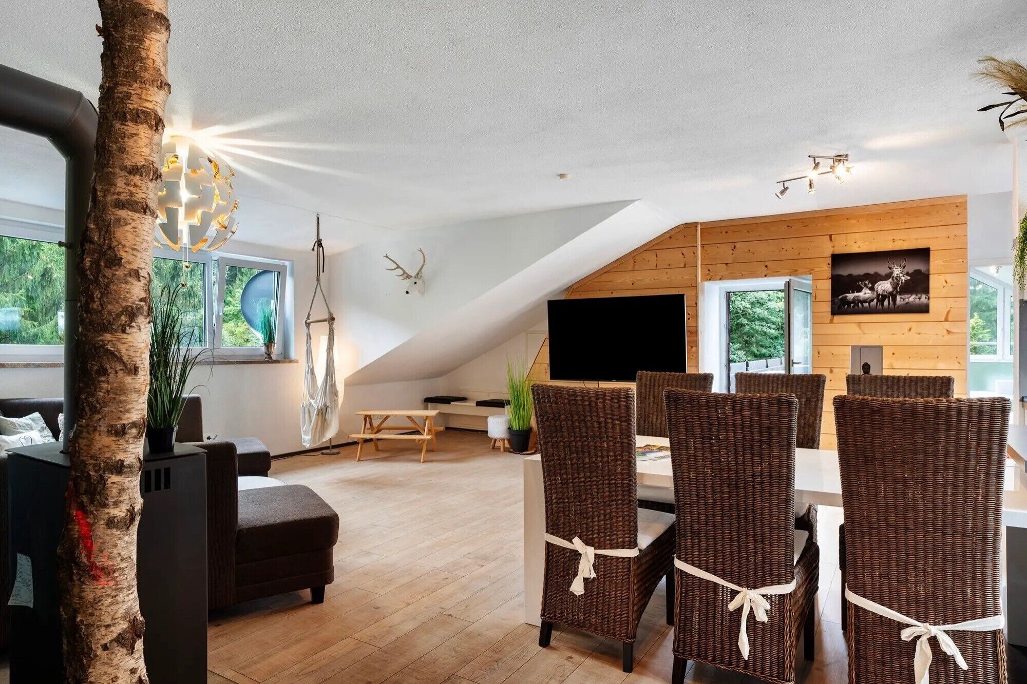 Un moderno espacio tipo loft con comedor, techo de madera y ventanas amplias.
