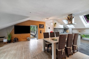 Ein moderner Loft-Wohnraum mit Essbereich, Holzelementen und Blick ins Grüne.