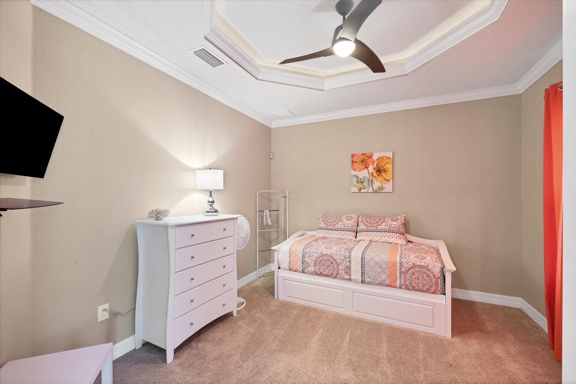 A bedroom with a bed, dresser, ceiling fan, and a wall-mounted TV.