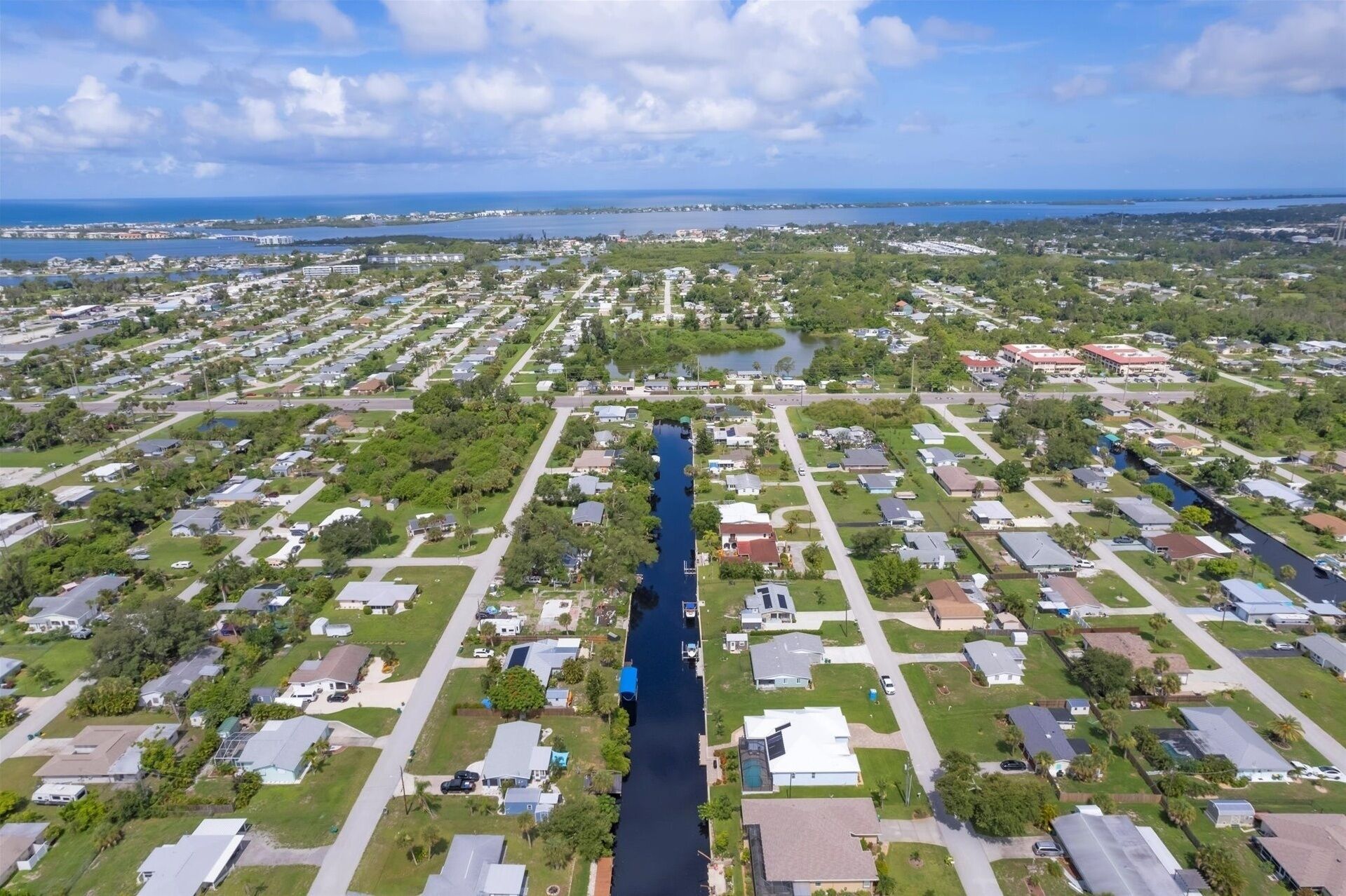 An aerial view of a residential area with a canal running through it, surrounded by houses and greenery.
