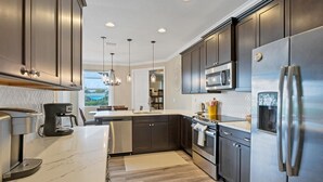 A modern kitchen with dark cabinetry, stainless steel appliances, and a marble countertop. - Englewood 5 Bedroom Pool Home 3 miles to Gulf Beaches! 5 Home (Englewood)