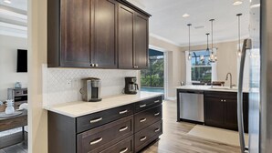 A modern kitchen with dark cabinetry, a white countertop, and a built-in dishwasher. - Englewood 5 Bedroom Pool Home 3 miles to Gulf Beaches! 5 Home (Englewood)