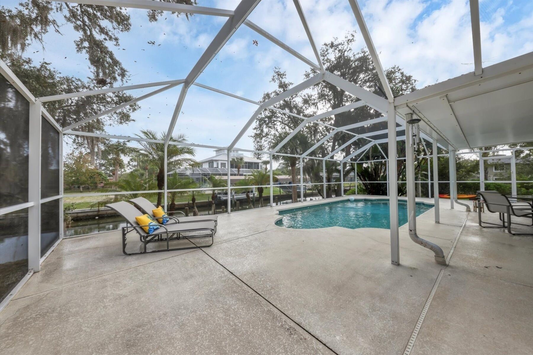 A covered outdoor swimming pool with lounge chairs and a view of the surrounding area.