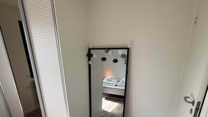Une pièce dotée d’une porte coulissante, d’un miroir orné de motifs circulaires et d’un lit avec une literie blanche.