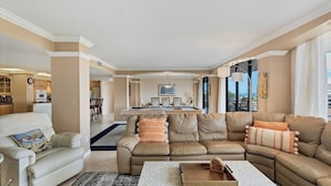 A spacious living room with a large L-shaped sofa, a coffee table, and a dining area with a pool table. - Anchorage Resort 3 bedroom Luxury Condo w Balcony, Pool Table, Near Beach 3 Condo (Siesta Key)
