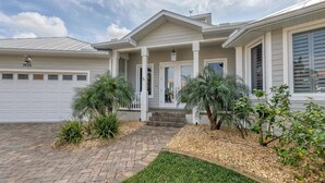 A two-story house with a covered porch, a garage, and a well-maintained front yard with shrubs and a brick pathway. - Height Of Luxury In Bird Section Of Punta Gorda Isles 3 Bedroom Home (Punta Gorda)