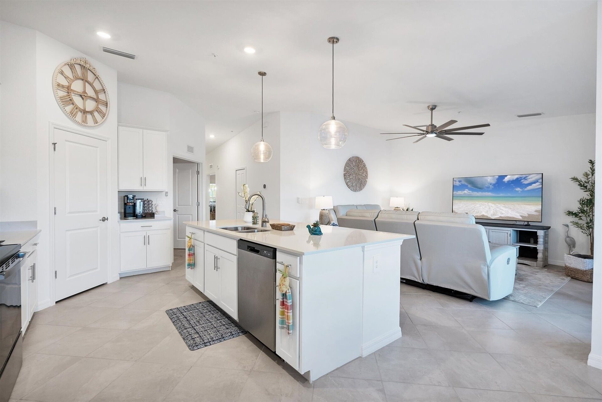 Een moderne keuken met witte kastjes, een centraal eiland, hanglampen en een plafondventilator.