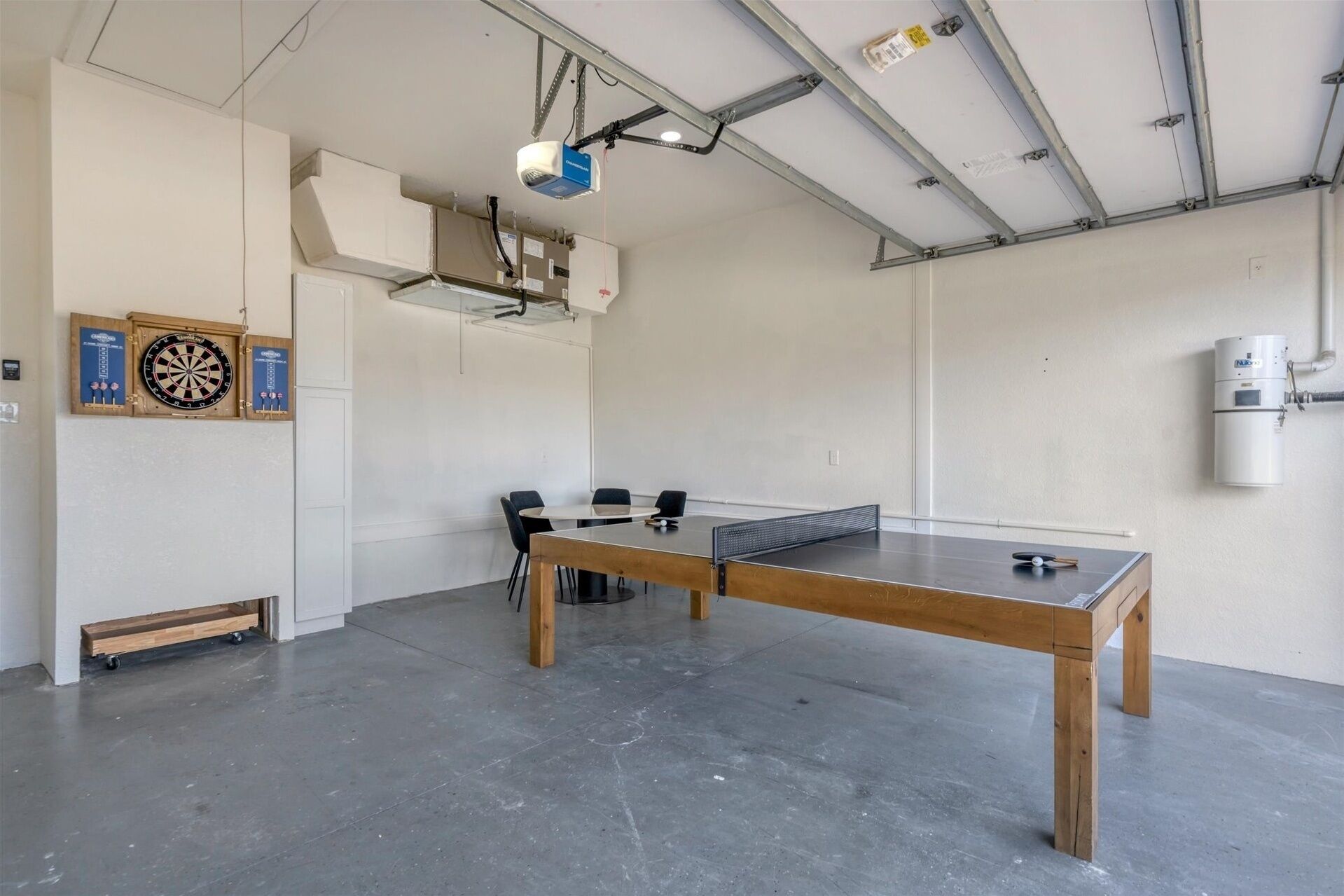 A spacious room with a ping pong table, a dartboard, and a water dispenser.