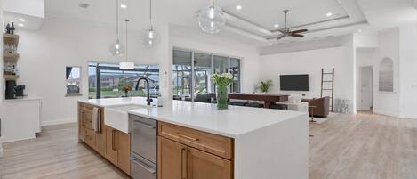 A spacious kitchen with a large island, wooden cabinets, and pendant lighting.
