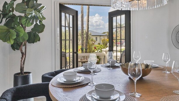 A dining area with a table set for four, a potted plant, and a view through open doors to the outside. - Punta Gorda Isles 4-Bedroom Private Pool Home on Canal 4 Home (Punta Gorda)