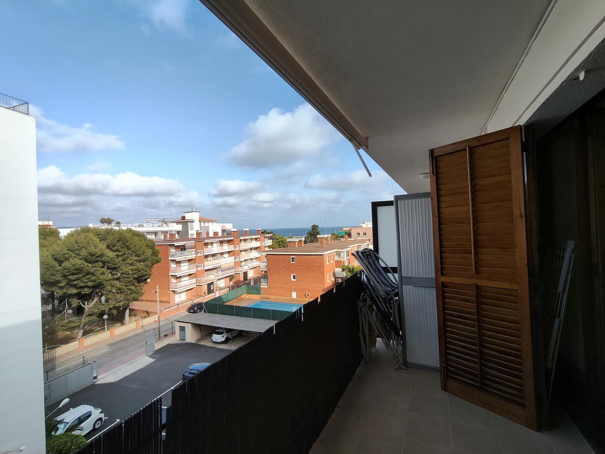 Un balcon donnant sur un quartier résidentiel, une piscine et une rue.