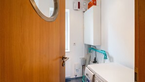 Ein Badezimmer mit Holztür, Waschbecken in Weiß, Spiegel, weißem Schrank und Heizkörper.