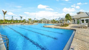 A large outdoor swimming pool with multiple lanes, surrounded by lounge chairs and palm trees. - Private Pool Home With Golf Course View Heritage Landing Golf Resort - 30 Night Minimum 3 Bedroom Home (Punta Gorda)