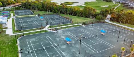 An aerial view of a multi-sport facility with tennis courts, a swimming pool, and a golf course.