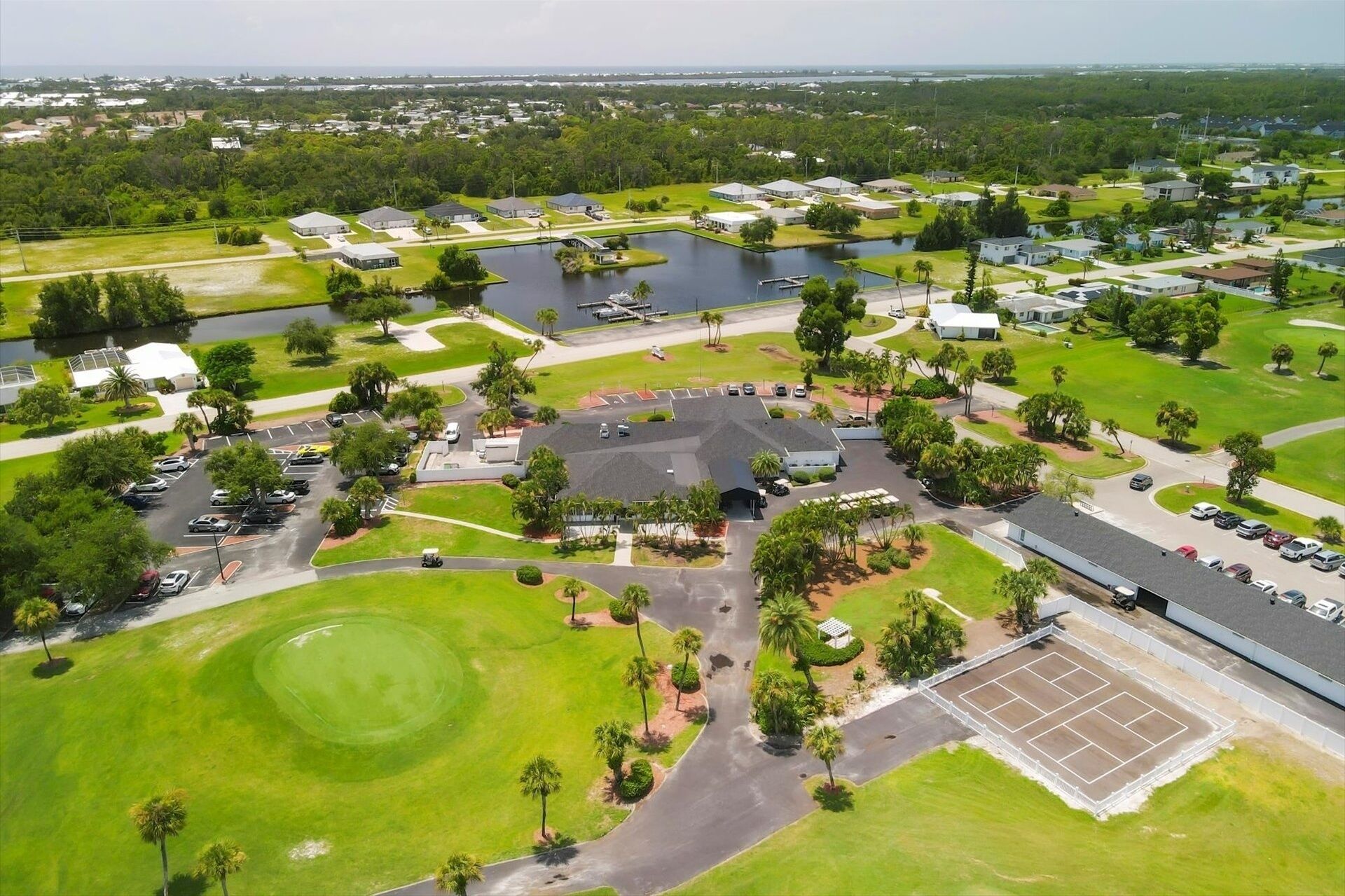 Vista aérea de una zona residencial con varias casas, un campo de golf y una gran masa de agua.