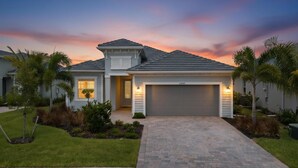 A two-story house with a garage, a well-maintained lawn, and palm trees. - Heritage Landing Resort 4 Bedroom House Private Pool+Spa 4 Home (Punta Gorda)