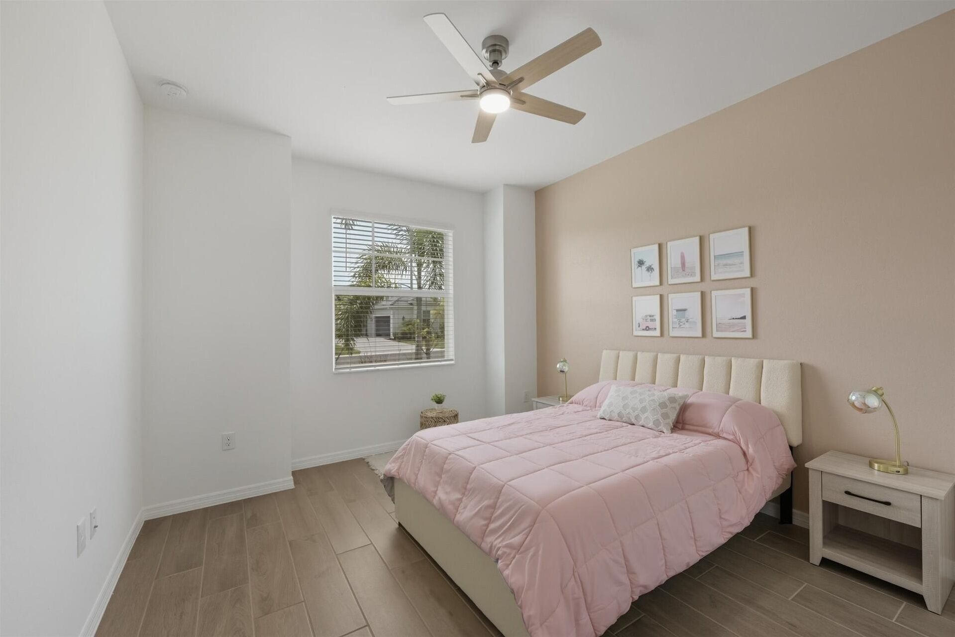 Une chambre à coucher avec un lit, un ventilateur de plafond, une fenêtre et une table de chevet avec une lampe.