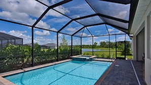 An outdoor swimming pool with a clear view of a lake and trees in the background. - Heritage Landing Resort 4 Bedroom House Private Pool+Spa 4 Home (Punta Gorda)