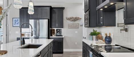 A modern kitchen with dark cabinetry, stainless steel appliances, and a central island.