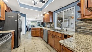 A modern kitchen with granite countertops, wooden cabinets, and a large island. - The Canal House Of Punta Gorda Isles, Pool, Pet Friendly, Kayaks, Bikes 3 Bedroom Home (Punta Gorda)