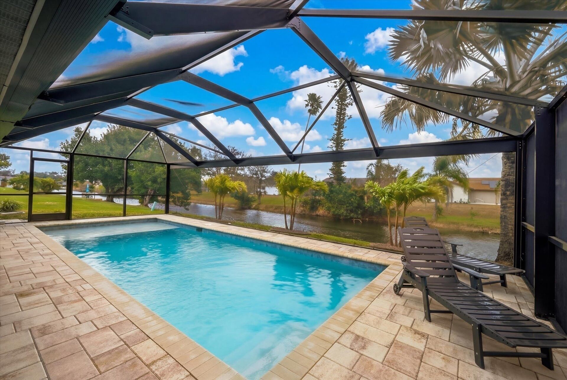 Una piscina techada con vista a un lago y palmeras.