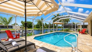 A pool area with lounge chairs, a pool, and a view of a body of water. - Punta Gorda 3-Bedroom Canalfront Pool Vacation Home with Dock 3 Home (Punta Gorda)