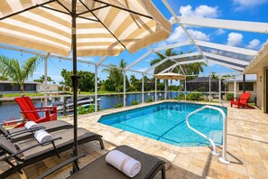 A pool area with lounge chairs, a pool, and a view of a body of water. - Punta Gorda 3-Bedroom Canalfront Pool Vacation Home with Dock 3 Home (Punta Gorda)