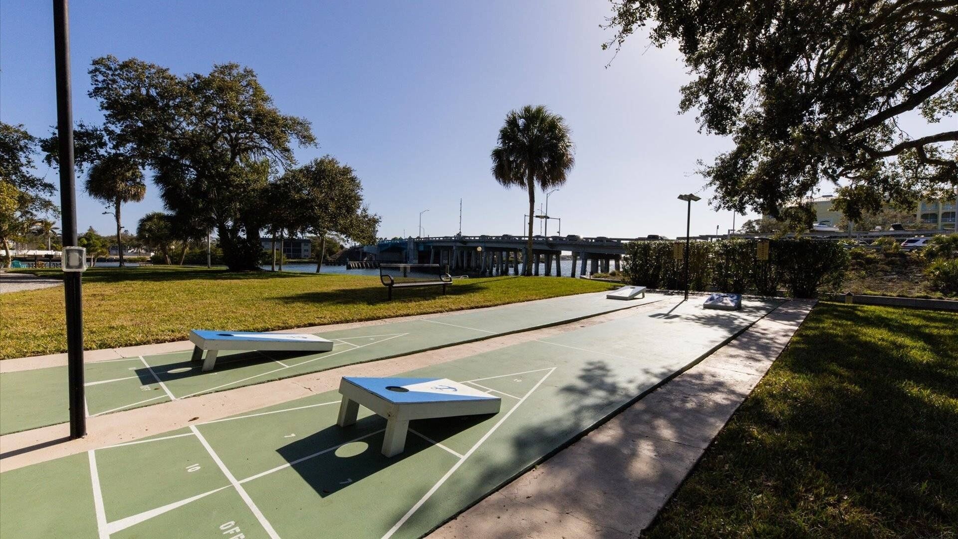 An outdoor basketball court with a green surface, white lines, and a bench.