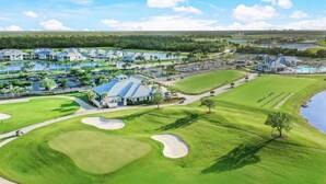 A golf course with a clubhouse, sand bunkers, and a water body. - Heritage Landing Golf And Country Club Vacation Condo 3 Bedroom Condo (Punta Gorda)