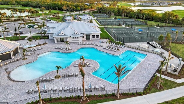 A resort with a large swimming pool, multiple tennis courts, and a golf course in the background. - Heritage Landing Golf And Country Club Vacation Condo 3 Bedroom Condo (Punta Gorda)